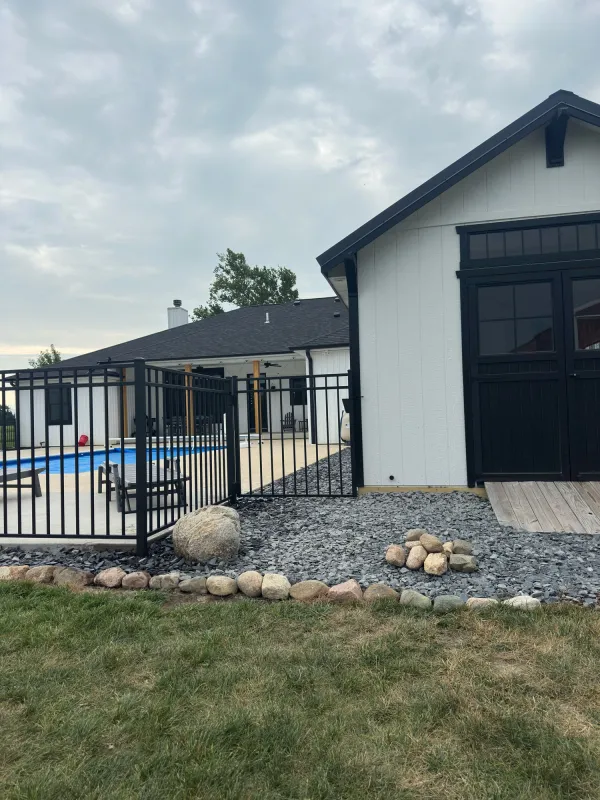 Black aluminum ornamental fence gate beside pole barn, Northern Indiana pool installation