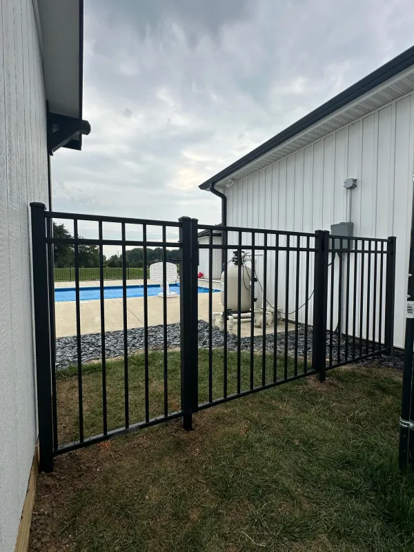 Black aluminum ornamental fence gate between buildings by pool equipment, Northern Indiana installation