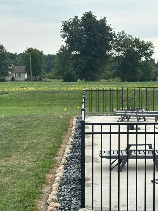 Black aluminum ornamental fence enclosing pool patio with wide yard view, Northern Indiana installation