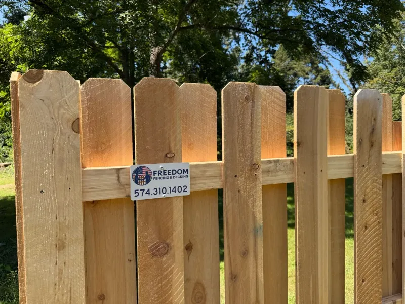 Close-up of cedar dog-ear privacy fence with Freedom Fencing sign, Northern Indiana installation