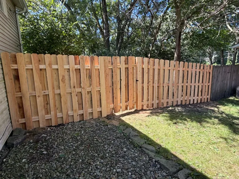 Cedar dog-ear privacy fence along house foundation, Northern Indiana installation