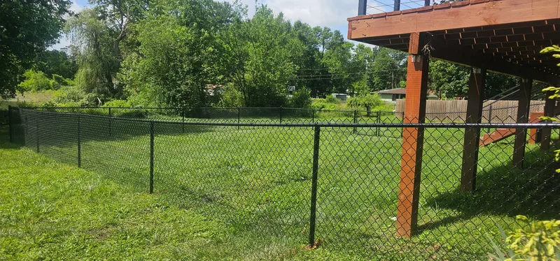 Black chain link fence installation beside wooden deck structure, Northern Indiana