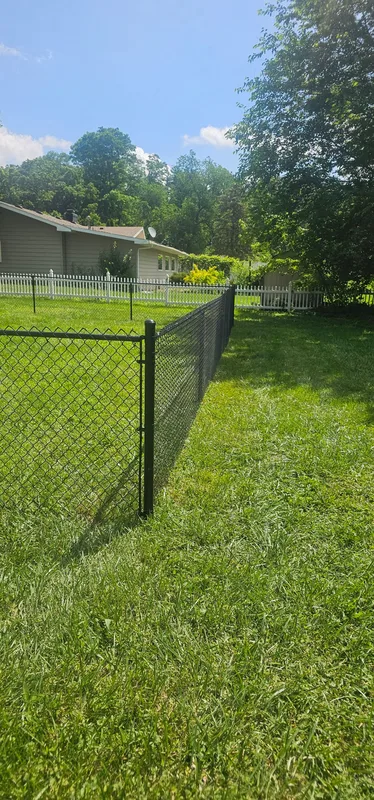 Black chain link fence corner post installation, residential yard in Northern Indiana