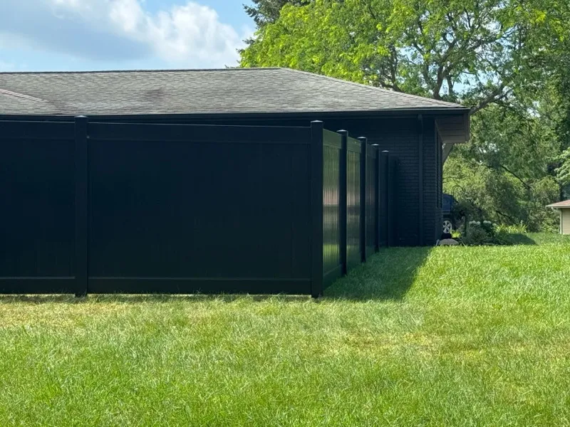 Black vinyl privacy fence along brick house, Northern Indiana installation
